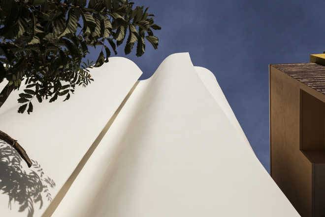 Cadence применяет особую технику кирпичной кладки, чтобы «свернуть» белый фасад клиники KMYF, примыкающей к индийскому храму